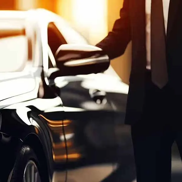 professional chauffeur waiting outside of a luxury limo while waiting for a corporate client