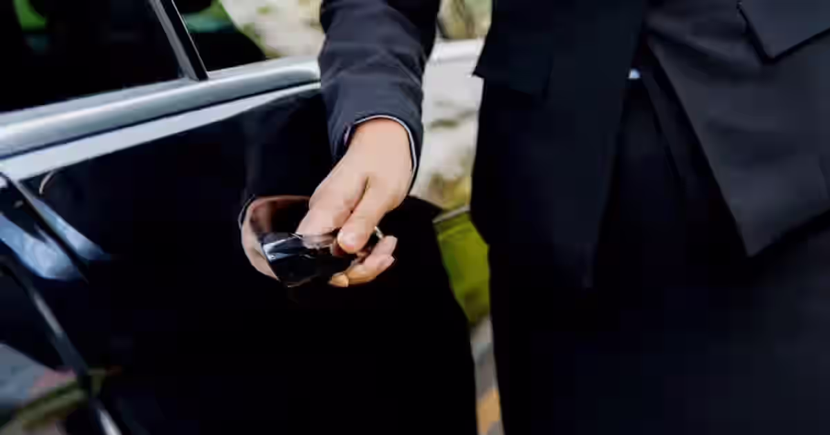 Chauffeur opening the door of a black luxury sedan for a passenger